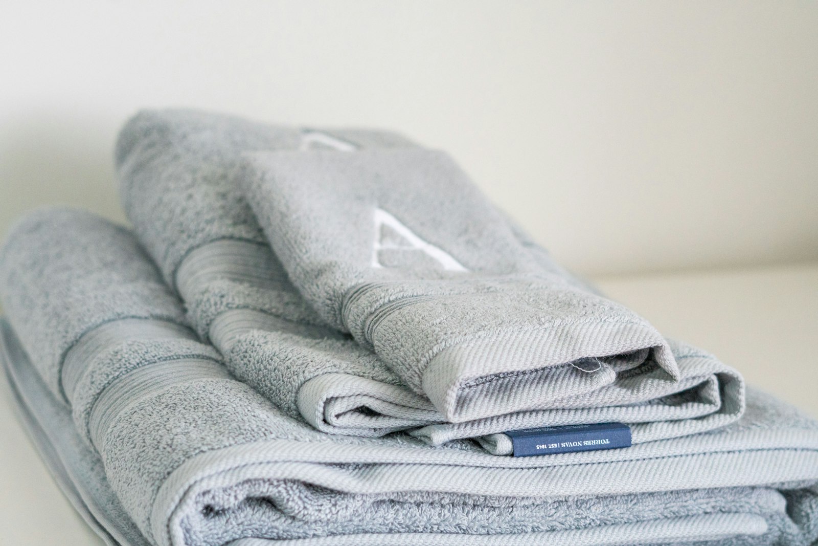 A stack of folded pale grey-blue cotton towels on a white surface